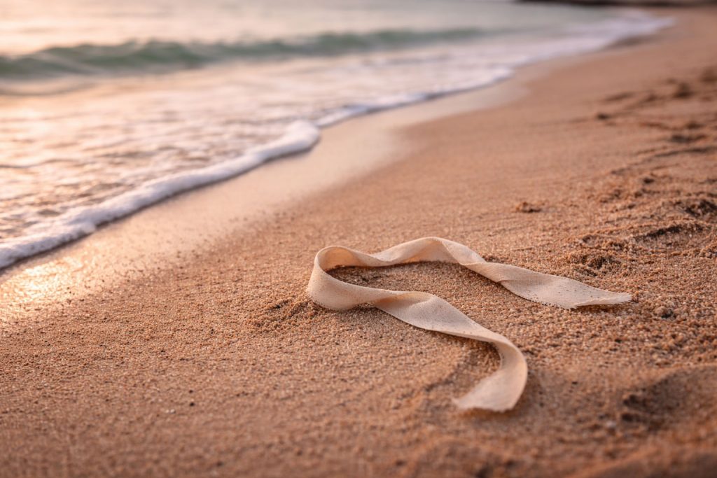 Ruban abandonné sur le sable de plage symbole de liens brisés - Traumatismes sexuels relations toxiques emprise sexologue Lunel