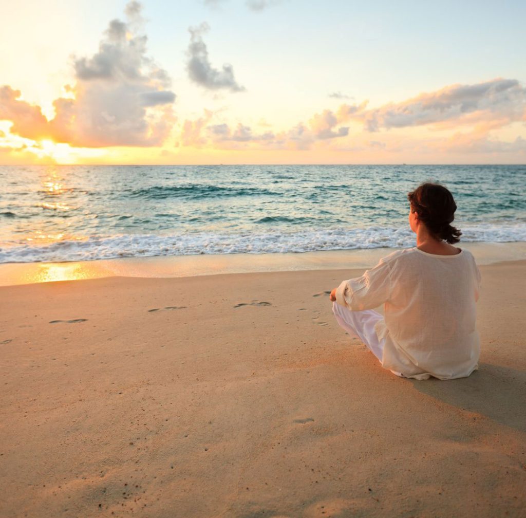 Femme assise seule sur le sable face à la mer contemplant l'horizon - Accompagnement dysfonctionnements sexuels vaginisme baisse désir Lunel